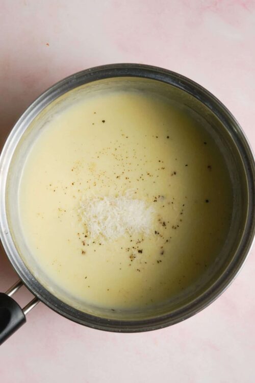 Creamy cheese sauce with grated cheese and black pepper on top.