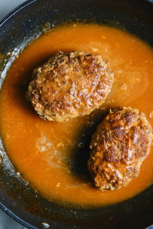 Juicy homemade meatloaf cooking in a skillet with rich tomato glaze. Classic comfort food recipe perfect for family dinners.