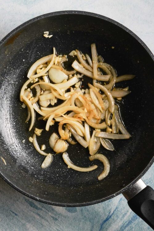 Sautéed onions and garlic in a black skillet.