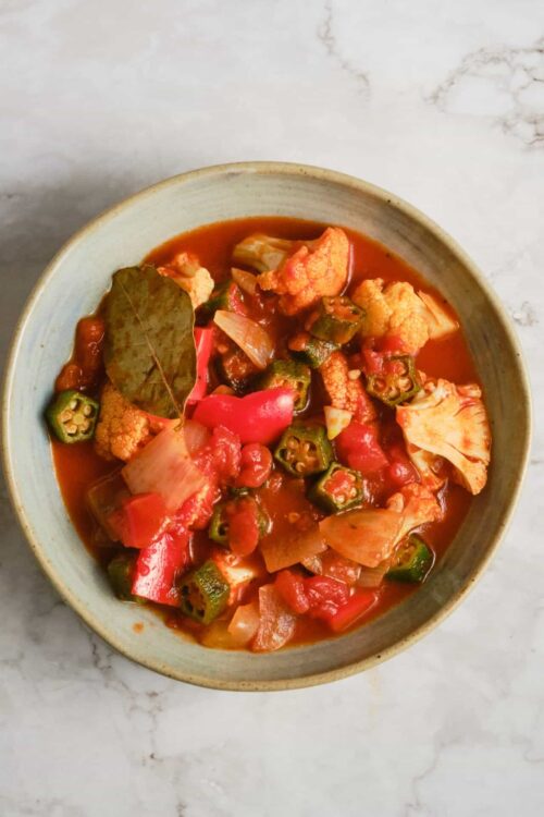 Hearty vegetable soup with cauliflower, okra, and tomatoes in a rustic bowl.