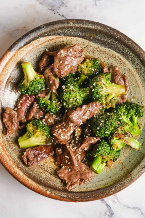 Savory beef and broccoli stir-fry with sesame seeds in a rustic bowl.