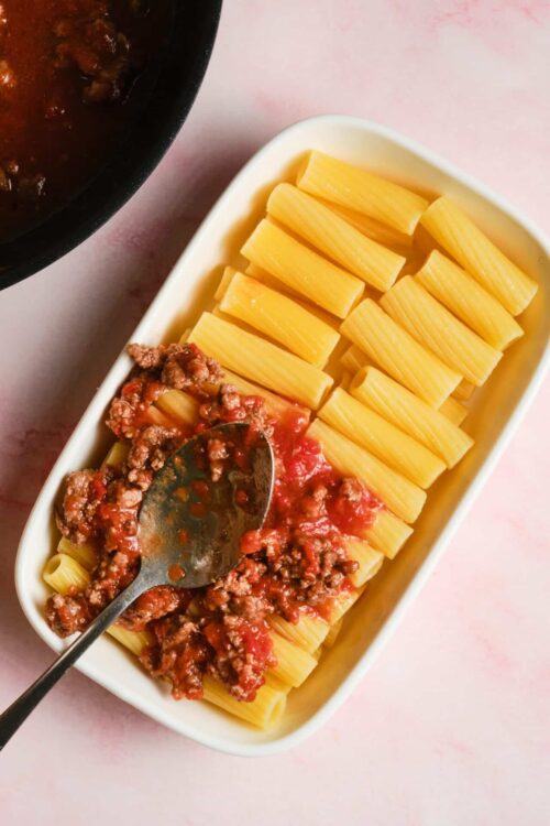 Baked pasta with meat sauce in a white baking dish, ready to bake or serve.