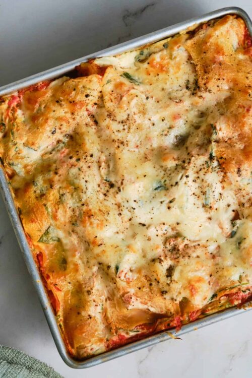 Creamy baked lasagna with melted cheese and fresh herbs in a baking dish.