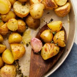 Golden roasted potatoes with herbs and garlic in a baking dish.