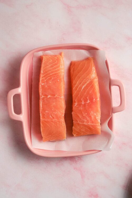 Fresh salmon fillets on a pink tray for cooking or meal prep, ideal for healthy recipes.