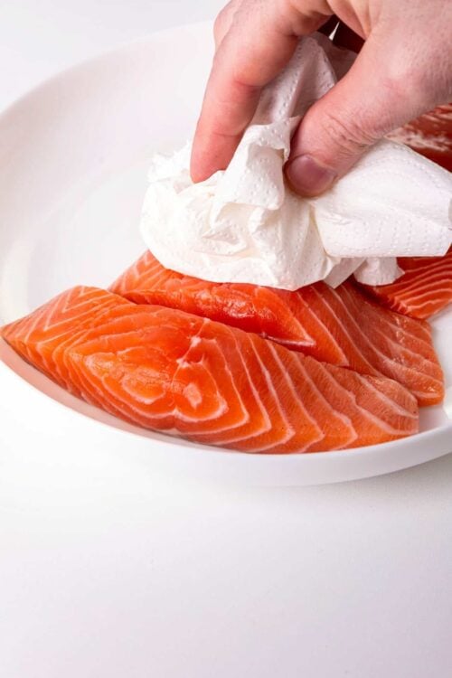 Fresh salmon slices with paper towel on top for preparing healthy seafood dishes.