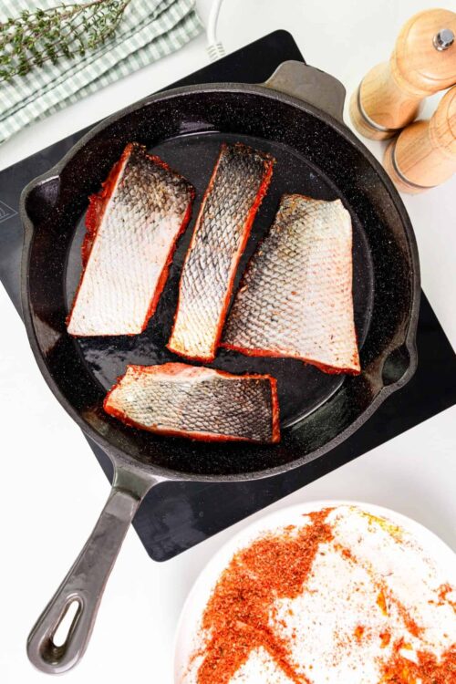 Freshly cooked salted fish fillets in a cast iron skillet, ready for a delicious seafood recipe.