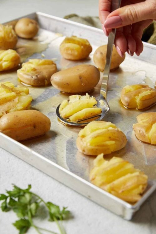 Baked potatoes being prepared and scooped out on a baking sheet for delicious potato recipes.