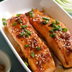 Juicy baked salmon fillets with glazed sauce and green onion garnish.