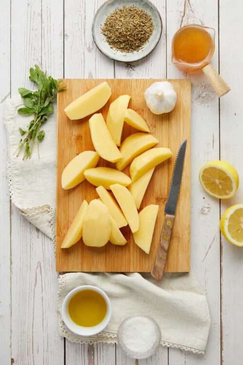 Freshly peeled potatoes on a wooden cutting board for homemade potato dishes.