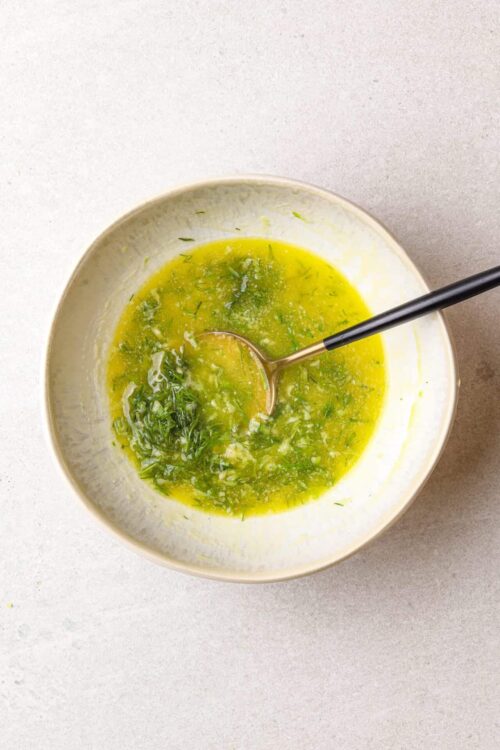 Chelsea green salad dressing with fresh herbs and olive oil in a white bowl.