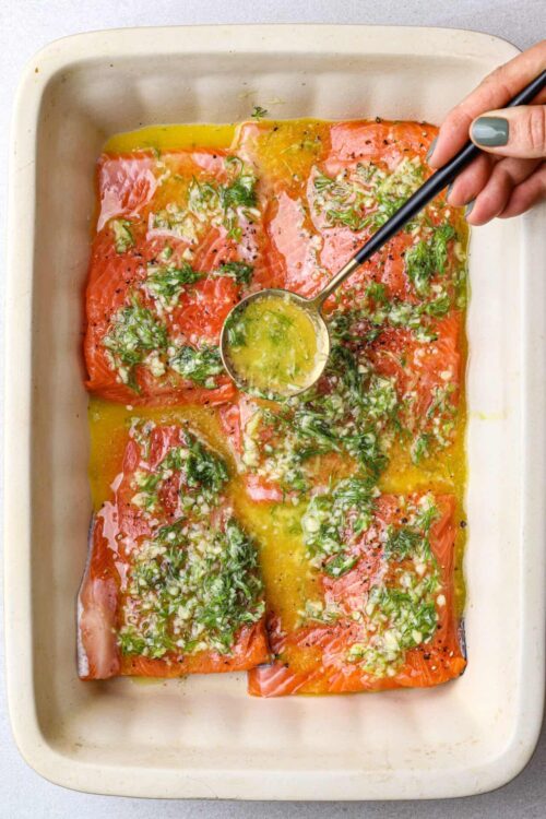 Baked salmon with herbs and lemon in baking dish.