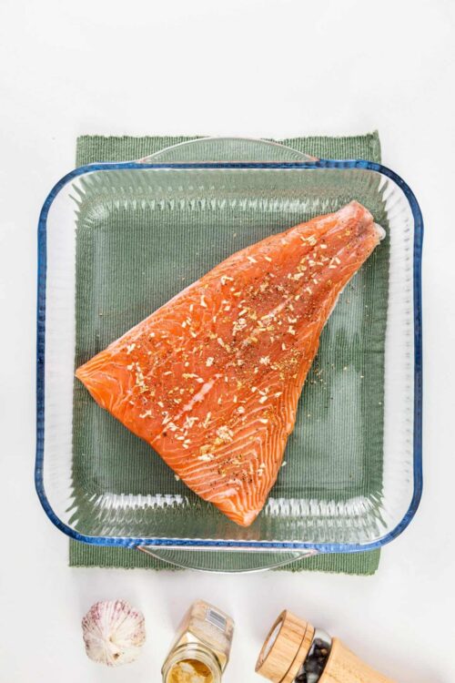 Fresh raw salmon fillet seasoned with spices, ready for baking or grilling.
