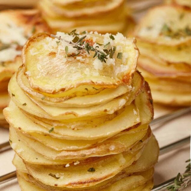 Thin sliced roasted potatoes garnished with herbs and grated cheese, served on a wire rack. Perfect for baked potato recipes and comfort food.