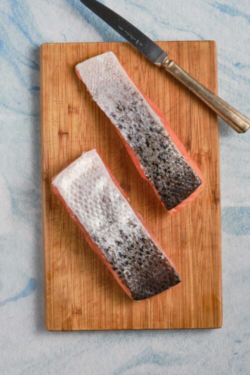 Fresh salmon fillets on a wooden cutting board for healthy seafood recipes.