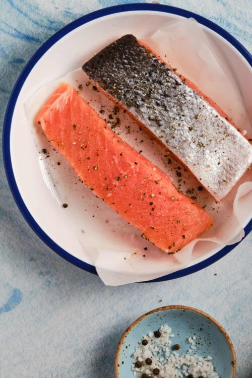 Fresh salmon fillets seasoned with salt, pepper, and spices ready for baking or cooking.