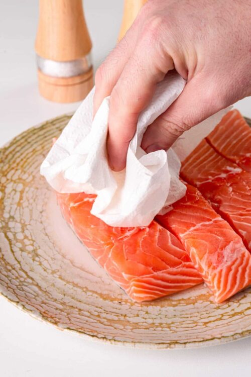Fresh raw salmon fillets on a decorative plate, ready for cooking or baking.