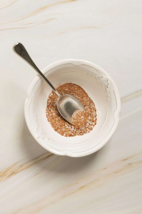 Spice mixture in a white decorative bowl with a spoon.