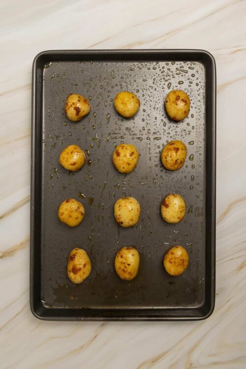 Golden roasted baby potatoes on a baking sheet.