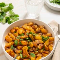 Golden roasted potatoes with herbs in a white baking dish.