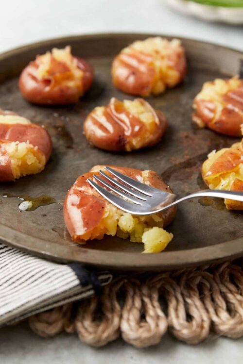 Buttered potato stuffed baked potatoes with cheese and bacon on a baking sheet.