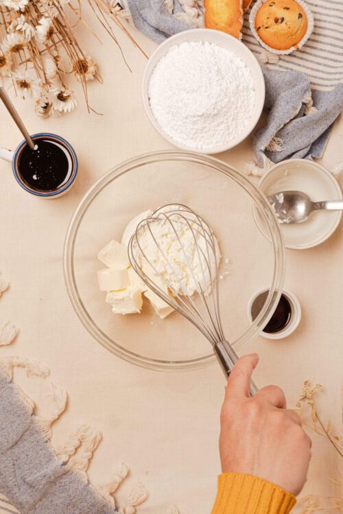 Cream cheese and butter in a mixing bowl with a whisk for baking recipe.