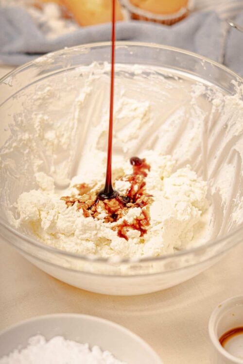 Butterscotch and vanilla ice cream being prepared in a glass mixing bowl with syrup drizzle on top.