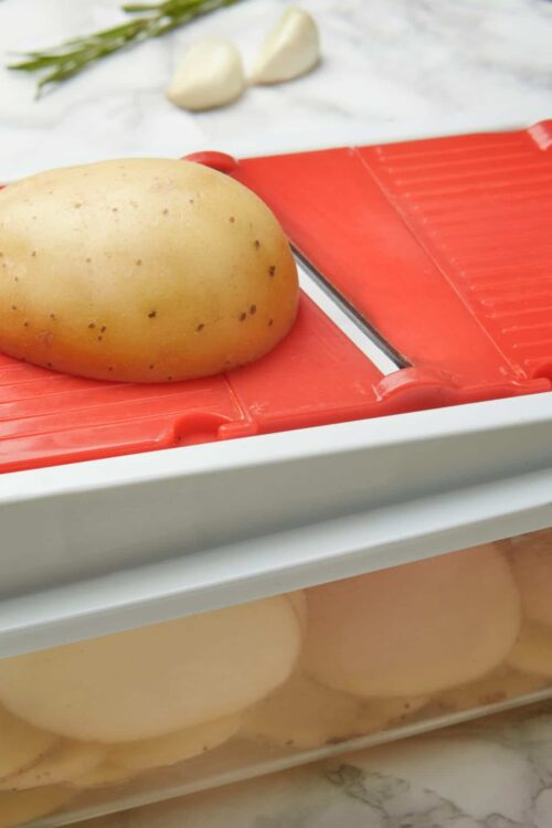 Golden russet potato on a red rubber potato masher, ready for mashing.
