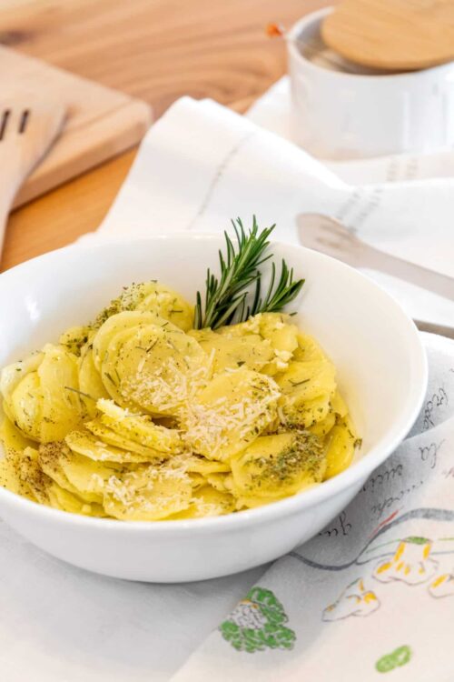 Creamy potato pasta with grated cheese and fresh rosemary garnish.