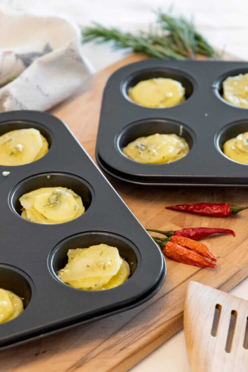 Creamy herb butter melting in muffin tins for baking or seasoning.