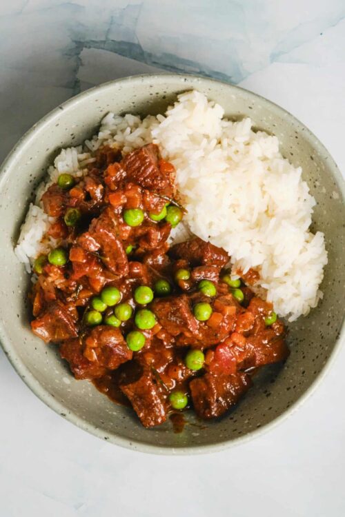 Savory beef stew with green peas and mashed potatoes in a bowl.