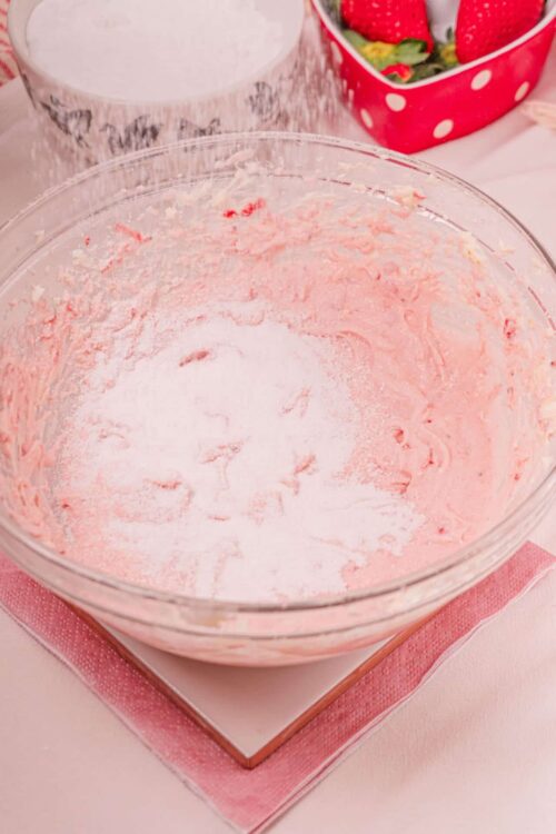 Sweet pink frosting in a glass bowl for baking and decorating.