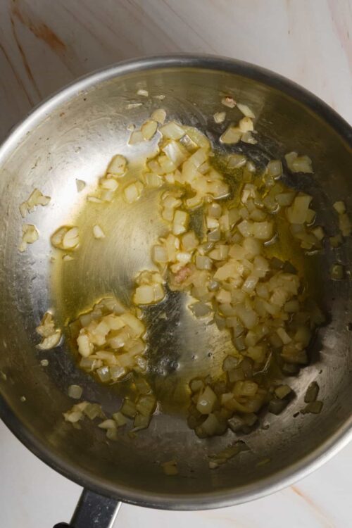 Sautéed minced garlic in a stainless steel pan.