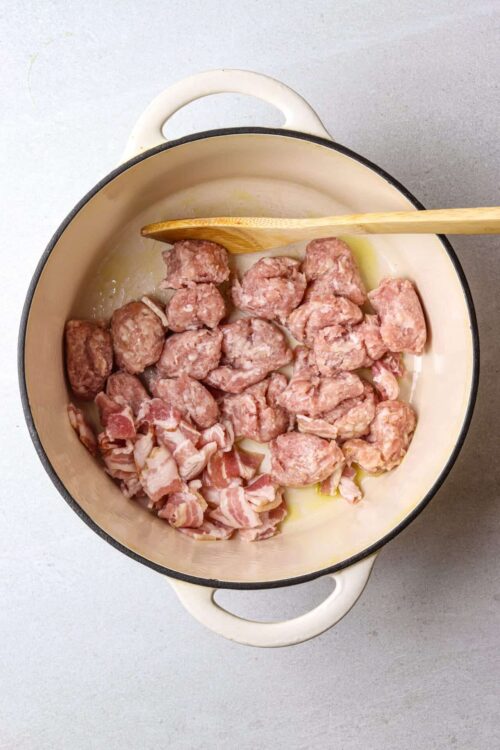 Seasoned raw meat and bacon cooking in a cast iron Dutch oven for flavorful recipes.