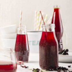 Refreshing homemade berry soda drinks in glass bottles with striped straws.