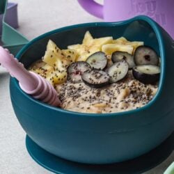 Fresh fruit breakfast bowl with pineapple, grapes, chia seeds, and creamy yogurt in a teal bowl.