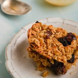 Butterscotch Oatmeal Cookie Bars with dried cherries on a white plate.
