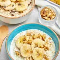 Sliced bananas with walnuts and honey on oatmeal in a blue bowl, healthy breakfast option.