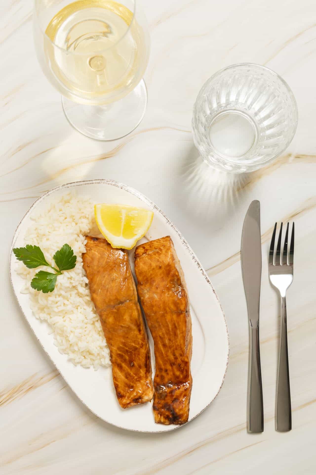 Grilled salmon with lemon, served with rice and parsley on white plate.
