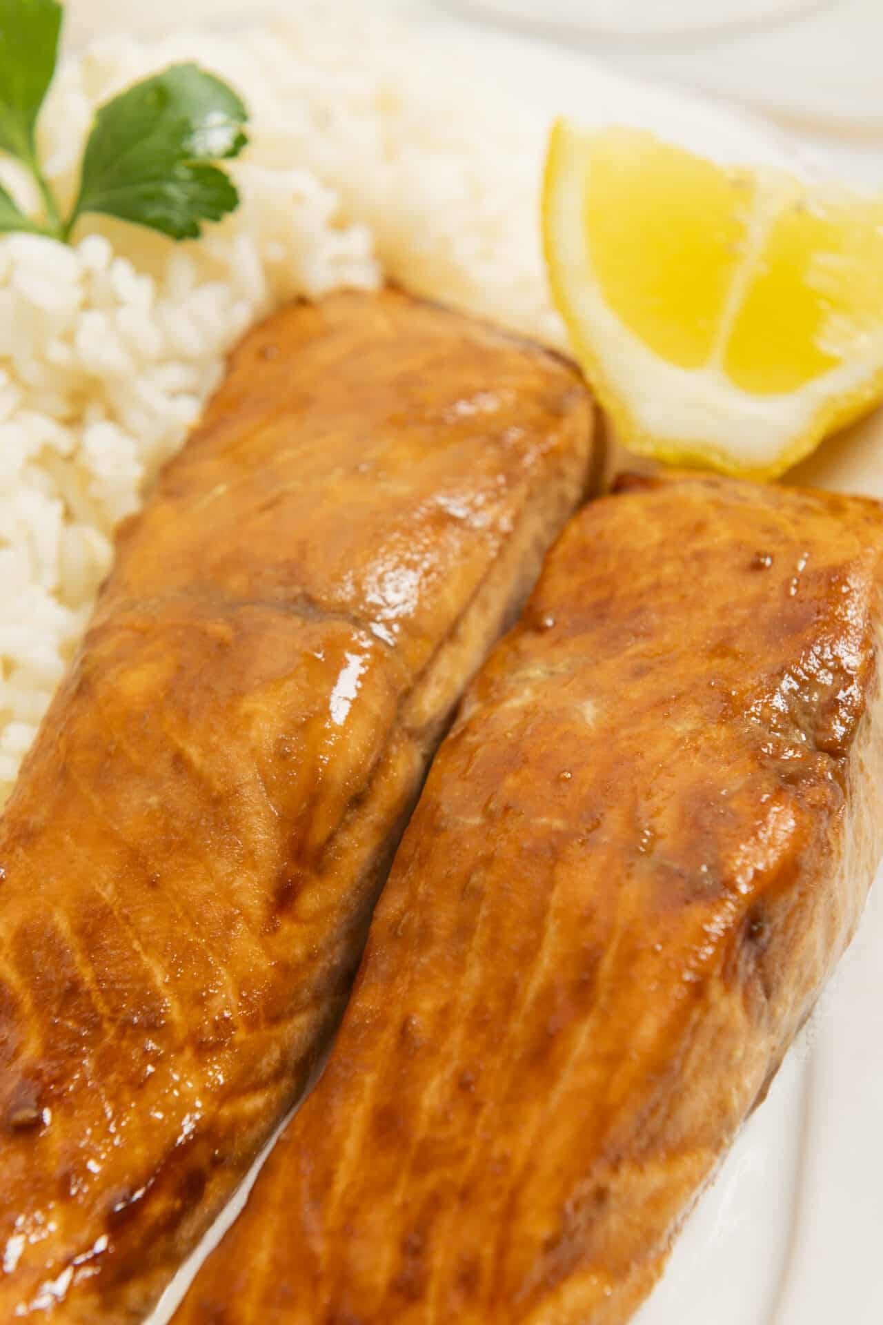 Pan-seared salmon fillets with lemon wedge and rice, fresh herbs, healthy seafood dish.