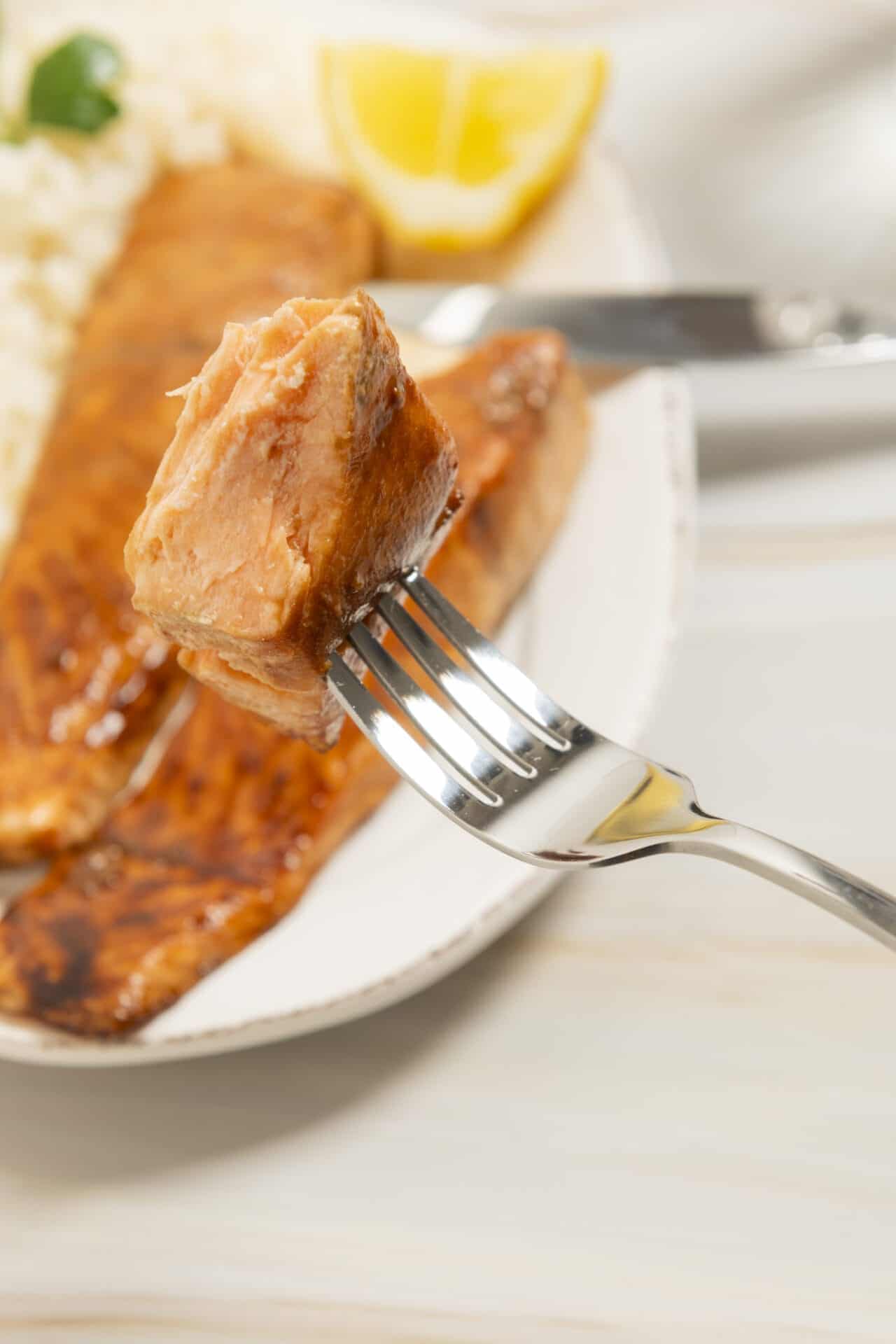 Tender salmon fillet with crispy skin, served on a white plate.