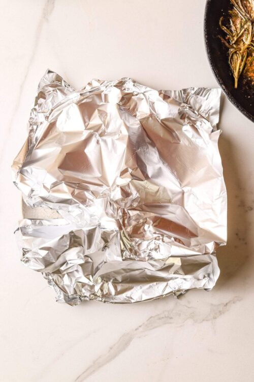 Aluminum foil wrapped baking dish on marble countertop for easy cleanup.
