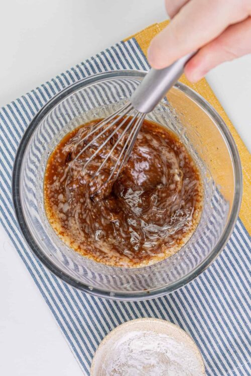 Sweet caramel sauce being whisked in a glass bowl with a hand mixer, perfect for baking and dessert recipes.