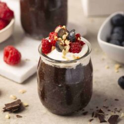 Sweetberry chocolate mousse jars topped with whipped cream and chopped nuts, perfect for dessert.