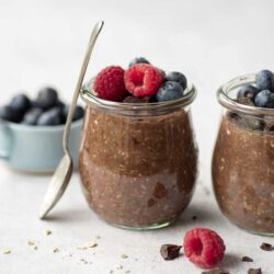 Creamy chocolate chia pudding with fresh berries in glass jars, healthy dessert option.