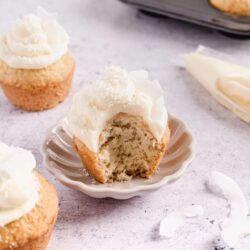 Buttermilk coconut cupcake with white frosting and shredded coconut topping.