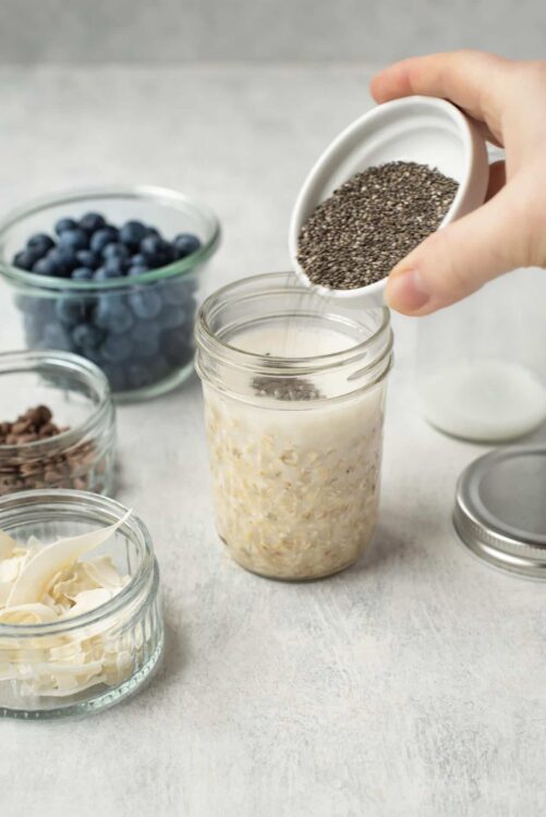 Fresh oats being added into a glass jar for a healthy breakfast or snack.