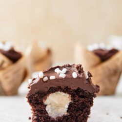 Decadent chocolate cupcake with vanilla center and white sprinkles, baked in muffin liners.