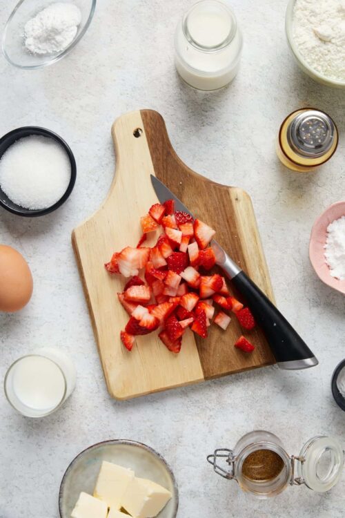 Diced strawberries on a wooden cutting board for baking or dessert recipes.