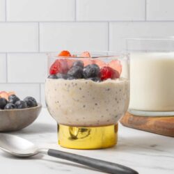 Fresh mixed berries topping creamy oatmeal in a clear glass.